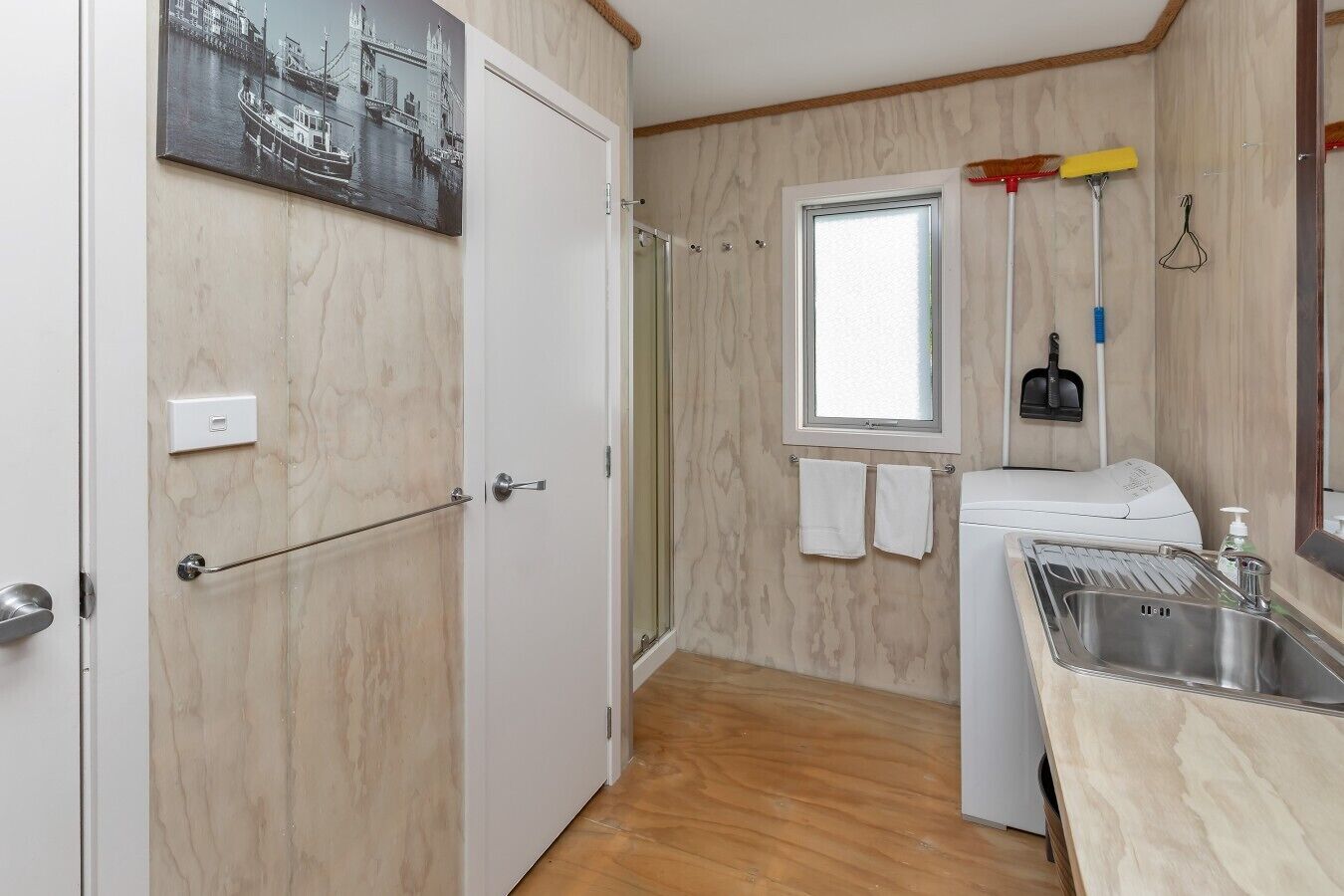 A compact kitchen with a washing machine, a window, and a sink.