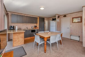 A compact kitchen with a dining area, wooden cabinets, a microwave, and a refrigerator.