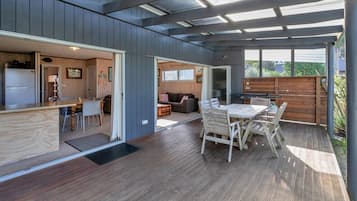 A modern kitchen with a built-in refrigerator, a dining area with a wooden table and chairs, and a patio with a wooden deck.