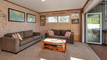 A cozy living room with two sofas, a coffee table, and a sliding glass door leading to an outdoor area.