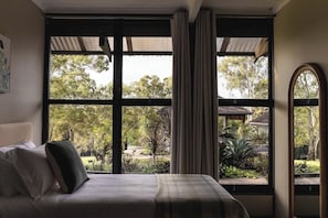 Ein Schlafzimmer mit großem Fenster, einem Bett und Vorhängen.