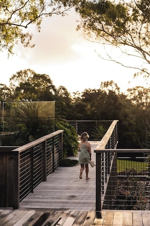 Eine Holzbrücke mit Metallgeländern, umgeben von viel Grün.