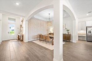 A spacious kitchen with modern appliances, a dining area with a chandelier, and a living space with a large window. - Heritage Landing Waterview and Pool Home (Punta Gorda)