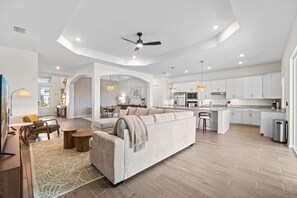 A spacious living area with a sofa, a dining table, and a kitchen in the background. - Heritage Landing Waterview and Pool Home (Punta Gorda)