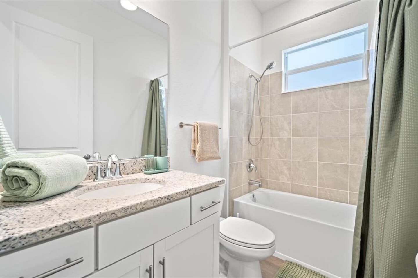 A bathroom with a sink, mirror, toilet, and bathtub.