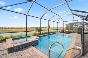 A swimming pool with a glass enclosure, a hot tub, and a covered seating area with a view of a water body. - Heritage Landing Waterview and Pool Home (Punta Gorda)