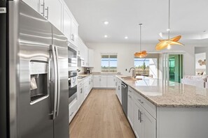 A modern kitchen with stainless steel appliances, white cabinetry, and a view to the outdoors. - Heritage Landing Waterview and Pool Home (Punta Gorda)