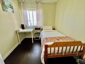 Ein kleines, sauberes Zimmer mit einem Bett, einem Schreibtisch und einem Stuhl.