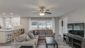 Un salon moderne avec un canapé, une table basse, un téléviseur et un ventilateur de plafond.