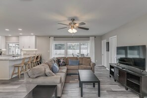 Ein modernes Wohnzimmer mit Sofa, Couchtisch, Fernseher und Deckenventilator.