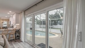 Une cuisine moderne avec un coin repas, une piscine et une porte-fenêtre coulissante donnant sur un jardin.