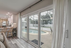 Eine moderne Küche mit Essbereich, einem Pool und einer Glasschiebetür, die in einen Garten führt.