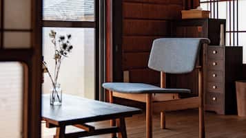 A traditional Japanese room with tatami flooring, a low wooden table, a chair with a grey cushion, and a sliding shoji screen.