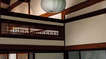 A traditional Japanese room with wooden beams, tatami flooring, a shoji screen, and a hanging paper lantern.