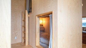 A compact room with a built-in bed, a small window with curtains, a shelf, and a wall-mounted light. - entohouse BAR&GUESTHOUSE (Seiyo)
