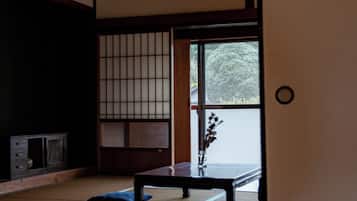 A traditional Japanese room with tatami flooring, a low table, a sliding door, and a hanging paper lantern.