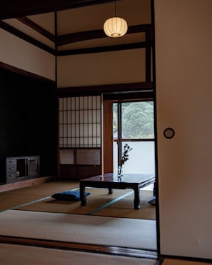Una habitación japonesa tradicional con suelo de tatami, una mesa baja, una puerta corredera y un farolillo de papel colgante.