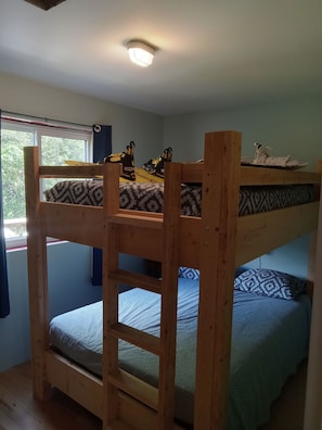 A bunk bed room with a window, wooden walls, and a ceiling light.