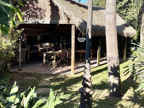 A thatched-roof outdoor dining area with a table and chairs, surrounded by greenery. - APARTBEACH OASIS YOUR PARADISE WITH TROPICAL POOL, JACUZZI (RIUDOMS)
