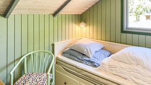 Una habitación pequeña y acogedora con una cama individual, una silla y un ventanal.