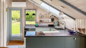 Una cocina moderna con una isla grande, electrodomésticos integrados y vistas al exterior.
