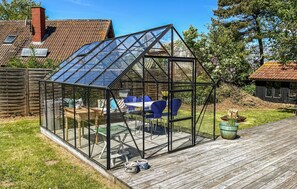 A glass greenhouse with a wooden deck, a table, chairs, and a potted plant. - Beautiful home in Humble with WiFi (Humble)