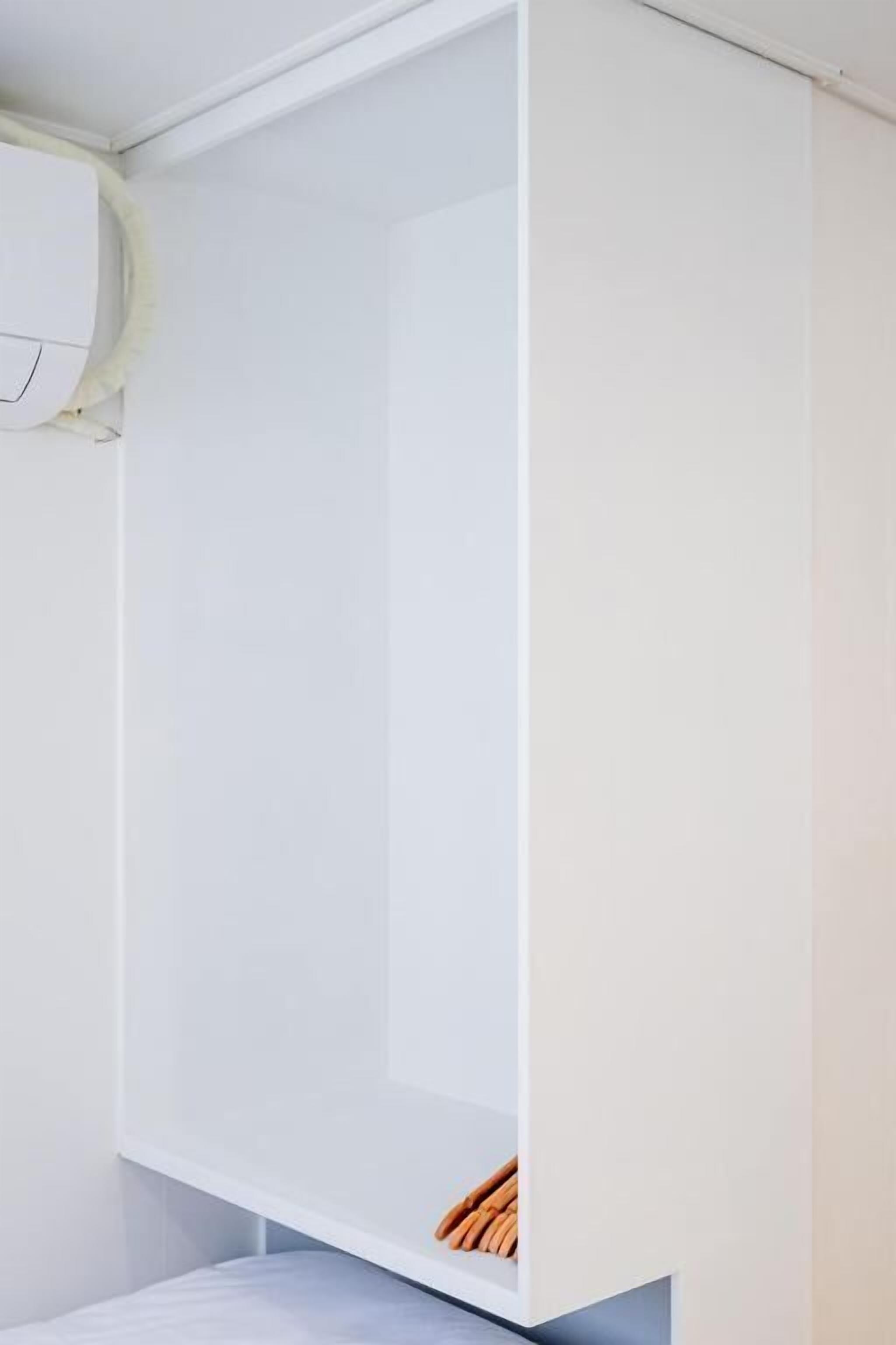 A white wardrobe with a lower shelf and a hanging rod.