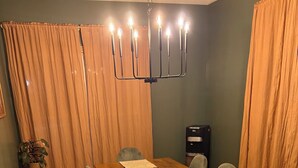 Un coin repas avec une table en bois, des chaises grises, un set de table en fibres tressées, un luminaire suspendu et une machine à café.