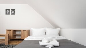 Un dormitorio moderno con una cama, almohadas, un escritorio de madera y dos obras de arte en la pared.