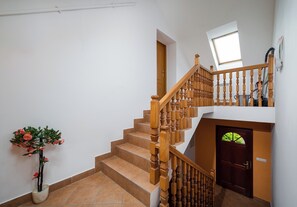 A staircase with wooden balusters, a potted plant, and a door with a window. - Bielsko-Biała Serenity Apartment #1 (Bielsko-Biała)