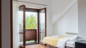A bedroom with a bed, a window, and a view of greenery outside. - Bielsko-Biała Serenity Apartment #1 (Bielsko-Biała)