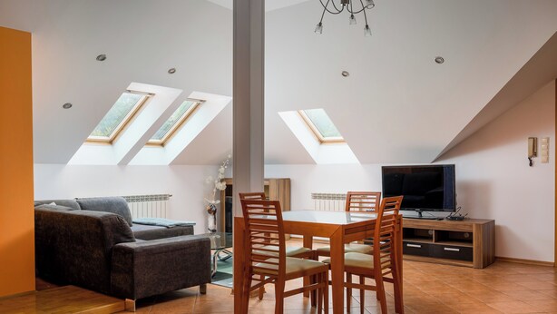 A modern living room with a sofa, dining table, chairs, a TV, and skylights. - Bielsko-Biała Serenity Apartment #1 (Bielsko-Biała)
