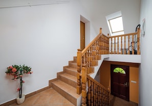 Un escalier avec des balustrades en bois, une plante en pot et une porte avec une fenêtre.