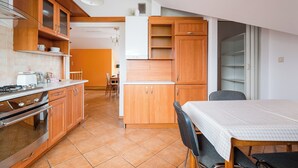 A kitchen with wooden cabinets, a stove, and a dining area with a table and chairs.