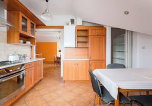 Une cuisine avec des meubles de rangement en bois, une cuisinière et un coin repas comprenant une table et des chaises.