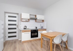 Eine moderne Küche mit weißen Schränken, einem Holztisch und einem eingebauten Backofen.