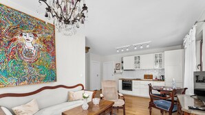 A living room with a sofa, a wooden coffee table, a patterned rug, and a dining area with a table and chairs.