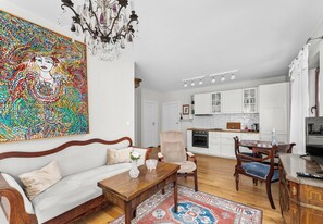 A living room with a sofa, a wooden coffee table, a patterned rug, and a dining area with a table and chairs. - Cracow Royal Charm Apartment (Kraków)