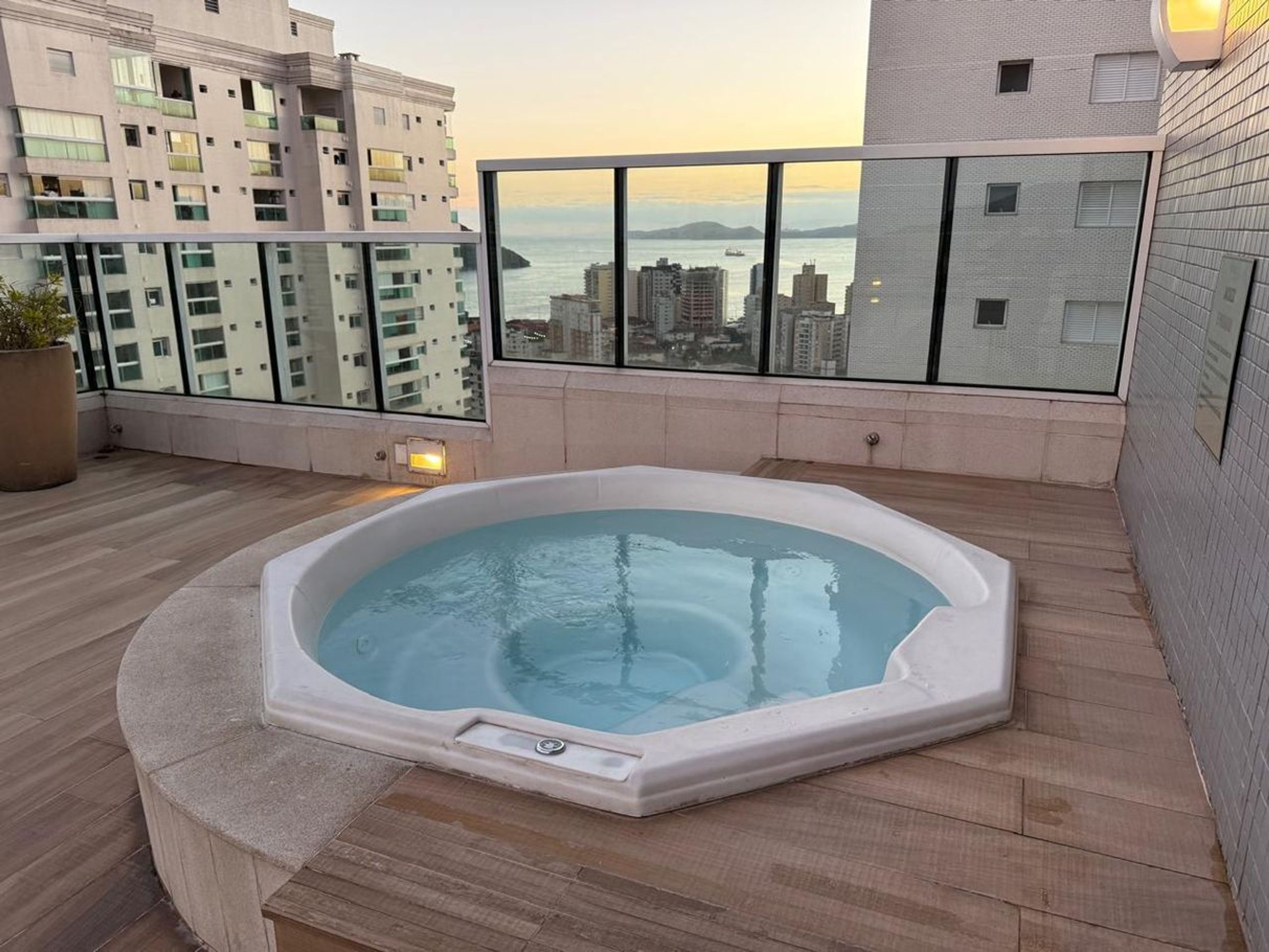 A rooftop hot tub with a city view, surrounded by a balcony with a glass railing.