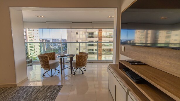 Un apartamento moderno con balcón, comedor y televisor grande.