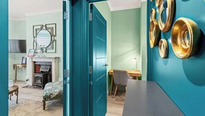 Une pièce aux murs de couleur turquoise, avec une cheminée, un bureau et un lit.