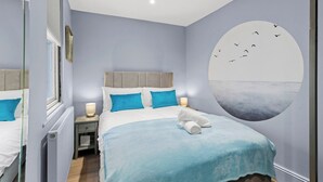 Une chambre à coucher avec un lit, une table de chevet, une horloge murale et une fenêtre.