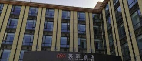 A modern hotel building with a prominent sign for 'MEHOOD HOTEL' and a series of vertical windows.