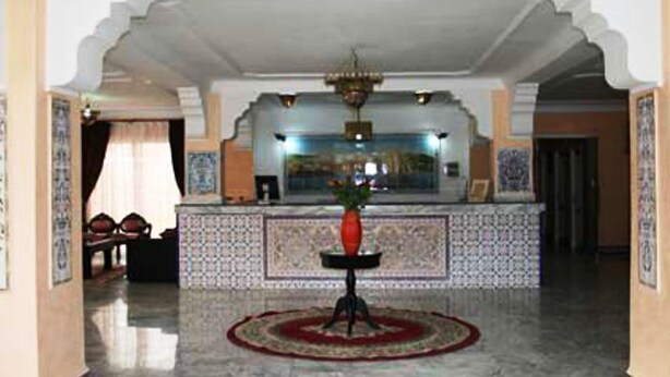 A lobby with a reception desk, a chandelier, and a tiled floor.