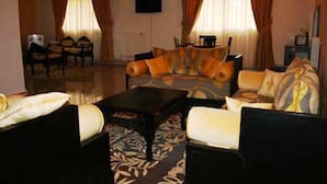 A hotel room with a sofa set, a coffee table, and a television mounted on the wall.