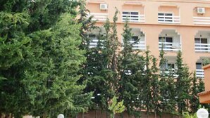 A multi-story building with balconies, surrounded by dense greenery.