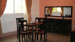 A room with a dining table, chairs, a mirror, and a cabinet.