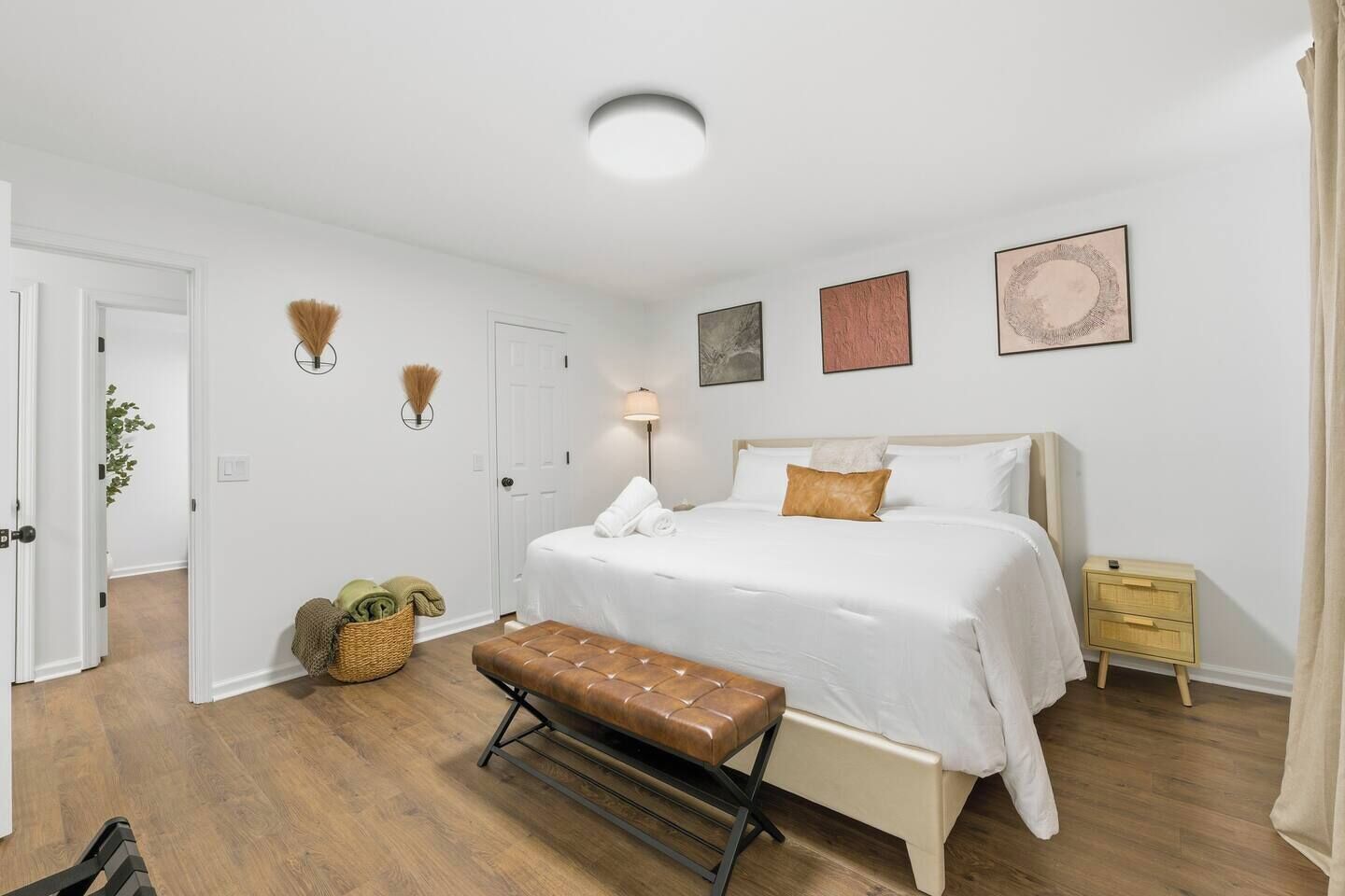 Un dormitorio con cama, mesitas de noche, un banco y lámparas fijadas a la pared.