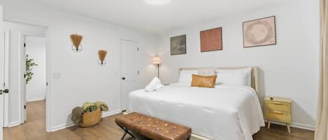 Un dormitorio con cama, mesitas de noche, un banco y lámparas fijadas a la pared.