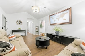 A modern living room with a sofa set, a round coffee table, a world map on the wall, and a console table with a vase. - KingBeds+Base10min+Hwy84+ChefKitchen+Spa Showers (Hinesville)